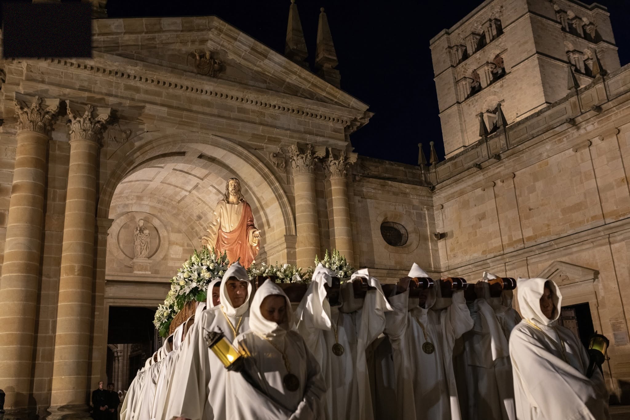 Hermanos con túnica cisterciense portando a Nuestro Señor Jesús de Luz y Vida a la salida de la Catedral