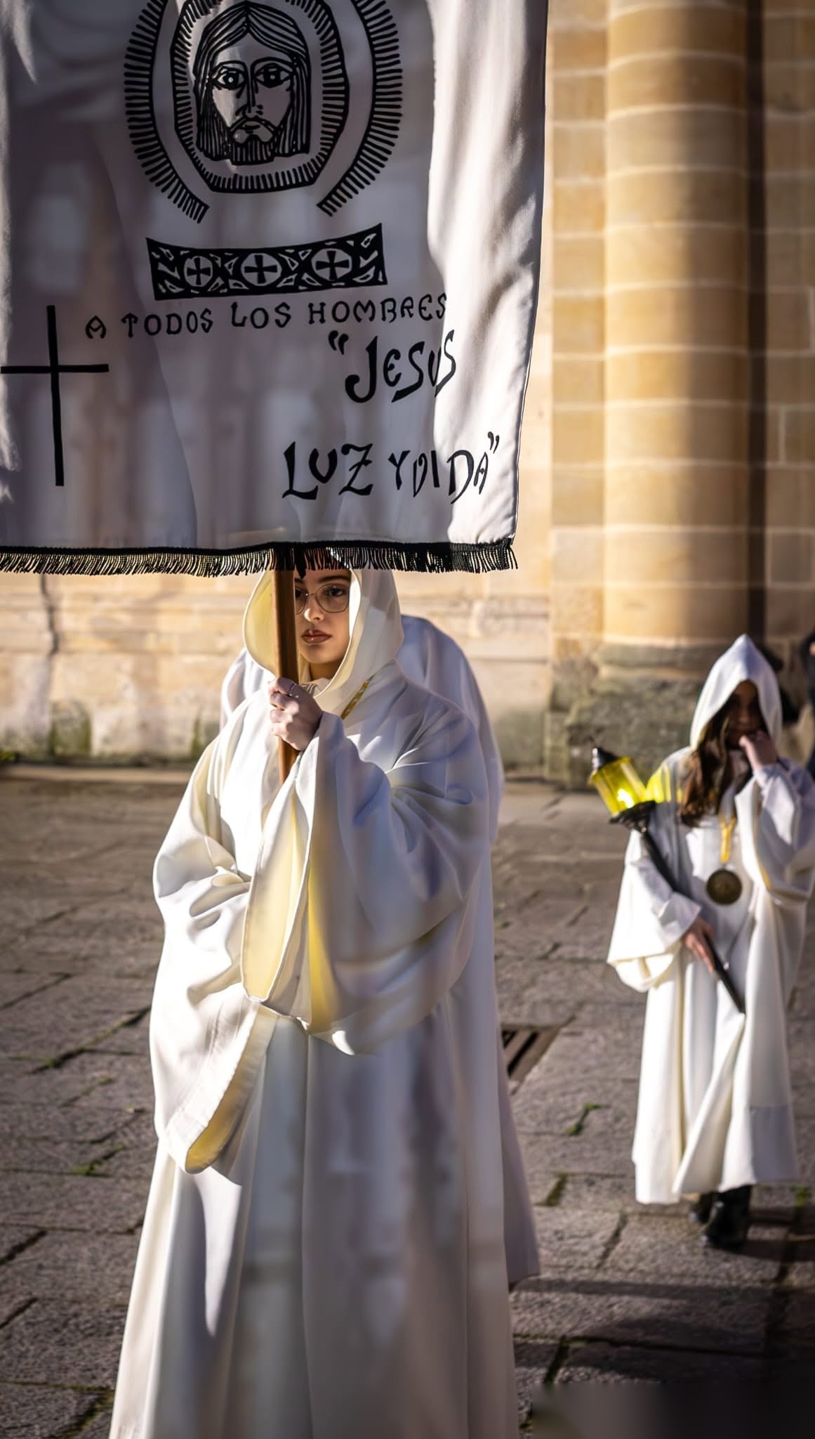 Hermana portando el pendón de la Hermandad, con el emblema de la Divina Faz